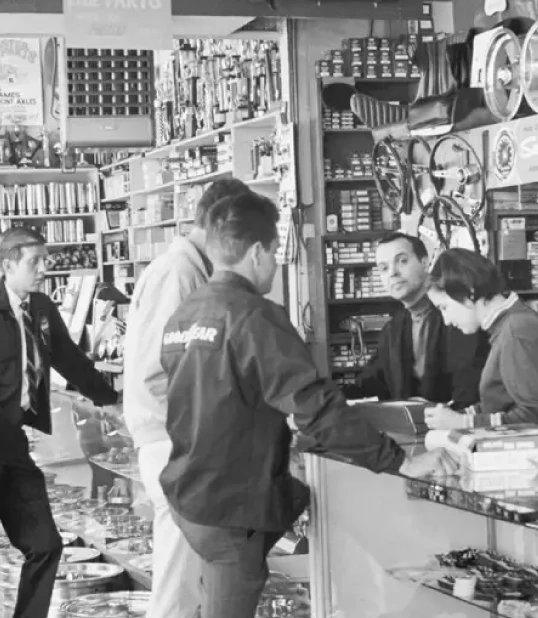 a group of people inside a auto parts store having a conversation.